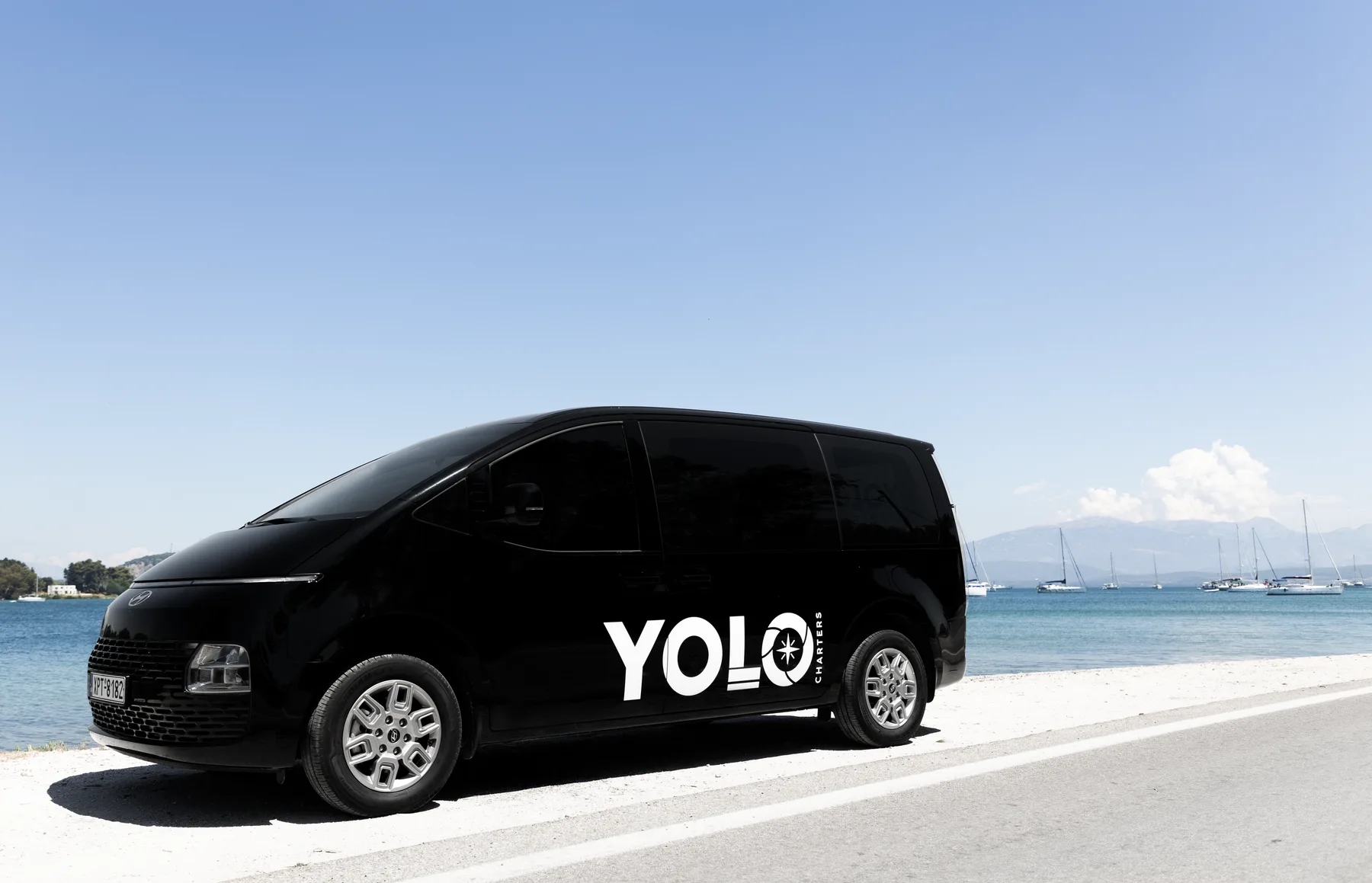 Black YOLO-branded Hyundai Staria van beside the waterfront