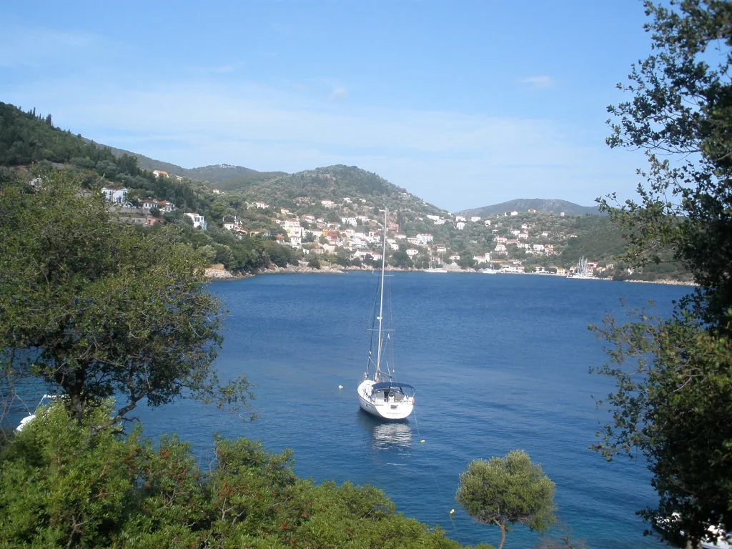 A sailing yacht in Kioni bay with the village on the wooded hillside beyond