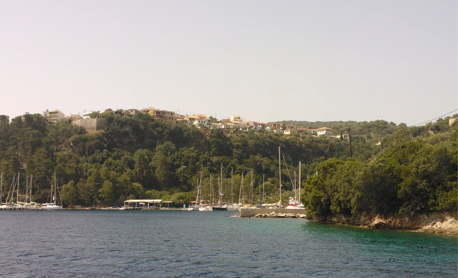 Spilia bay with moored yachts and the hillside village of Spartochori on Meganisi