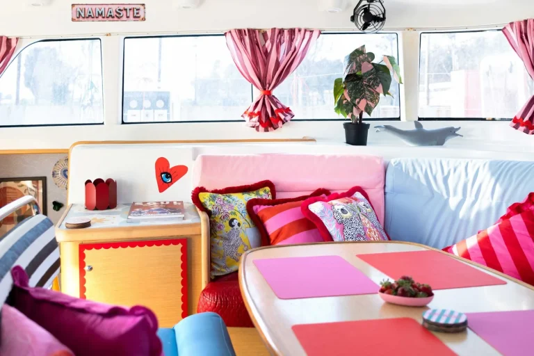 White seating, colourful cushions and a pink table inside Strawberry’s saloon