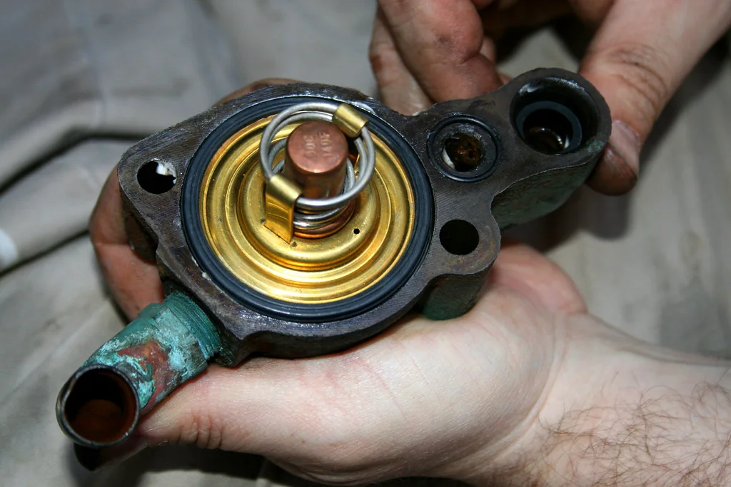 Hands assembling a marine cooling-system thermostat and seal.